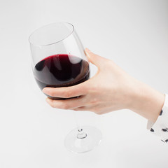 A glass of red wine in a female hand on a white background
