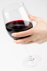Female hand holding red wine glass on white background