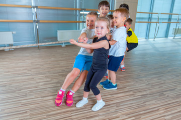Children and recreation, group of happy multiethnic school kids playing tug-of-war with rope in gym