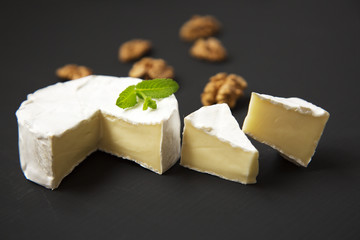 Cheese camembert or brie with walnuts on dark background. Side view.