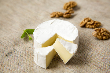 Cheese camembert and slices with walnuts. Milk production. Side view.