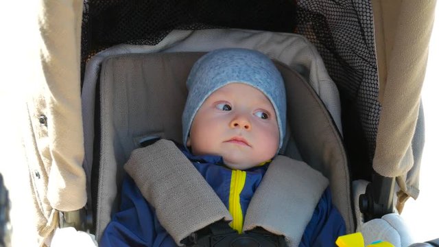 Little and very beautiful boy sitting in the pram