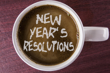 Writing note showing  New Year'S Resolutions. Business photo showcasing Goals Objectives Targets Decisions for next 365 days written on Coffee in White Cup on the wooden background.