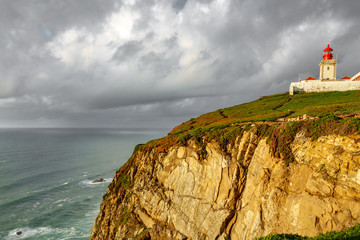 Fototapeta na wymiar Lighthouse on top of cliff at dusk