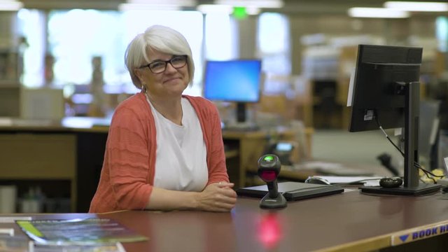 College librarian smiling and talking to students.