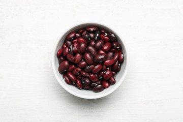 Red kidney beans in a white ceramic bowl on a wooden table