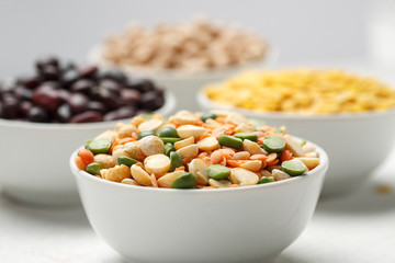 Different beans in bowls on a white wooden table