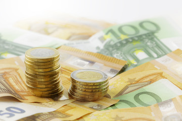 Euro coins in pile on Euro banknotes, background.