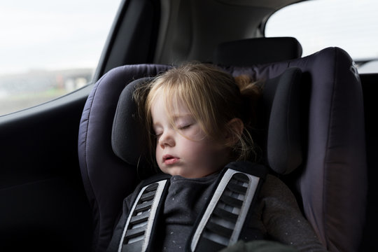 Tired little girl sleeping in the back of the car