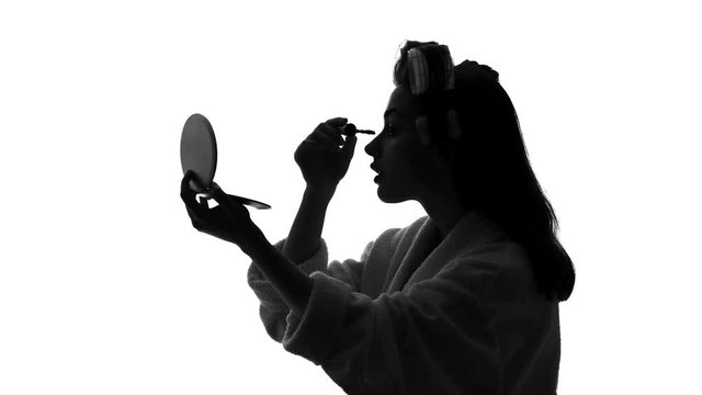 Beautiful young woman applying mascara makeup in front of mirror, beauty