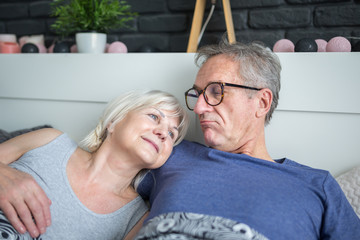 Happy senior couple lying together in bed