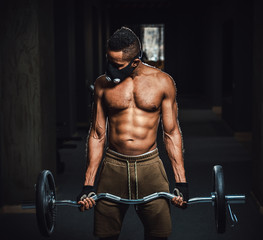 Fototapeta na wymiar african american athletic man in mask looking at arm and lifting barbell on biceps. Exercise for biceps with barbell. black man in gym