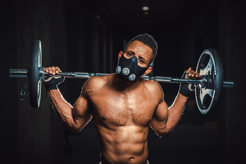 Fototapeta na wymiar african american athletic strong man holding barbell on shoulders in gym. black man poses with barbell in gym close-up