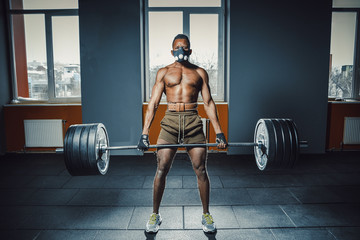 african american athletic man in sport mask doing deadlift with heavy barbell. black man lifting...