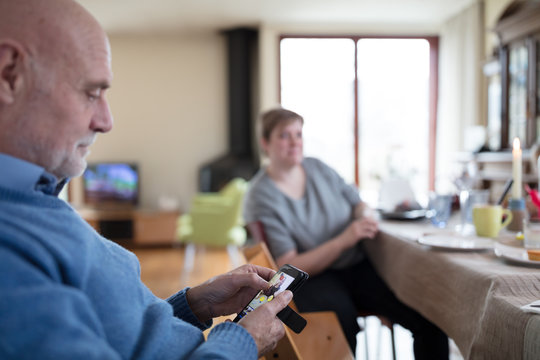 Senior man editing images on mobile phone in living room