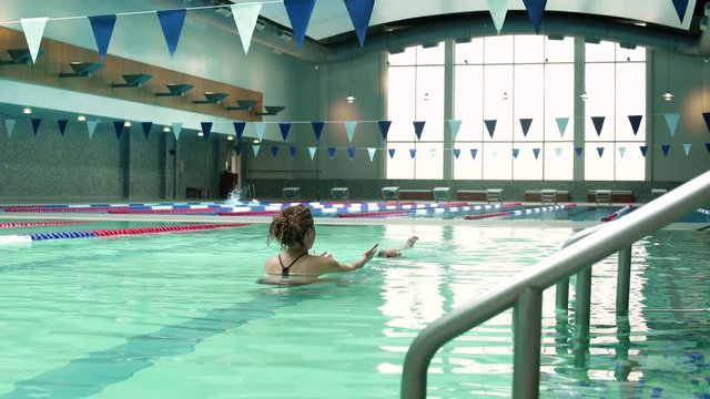 Daughter swimming towards her mother in a pool