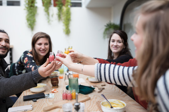 Happy friends toasting with healthy juices at table