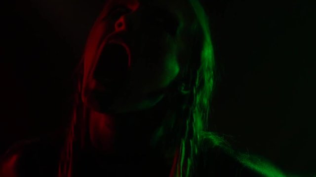 In a multicolored lighting, the girl screams in a magical ritual