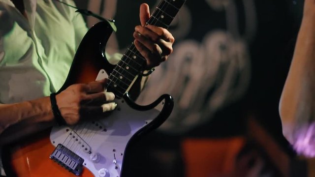 Male musician plays bass guitar at a rock concert.