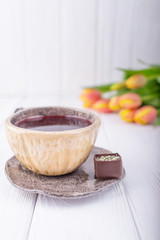 Hibiscus tea, luxury chocolates candy and flowers orange tulips on a white wooden background