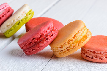 Different types color of macaroons on white wooden background