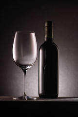 bottle of wine with empty glass on black