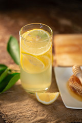 Lemon juice with honey on wooden table,  lemons and sage leaves