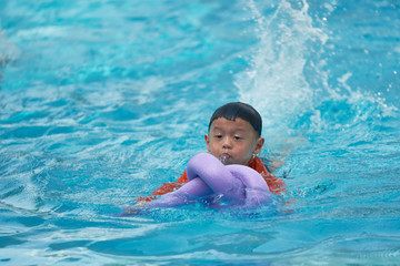 Fototapeta na wymiar Boy practice swimming with noodle foam floater