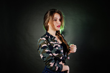 Handsome brunette girl wear military shirt and jeans, posing at studio against gray background. Studio model portrait.