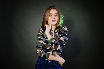 Handsome brunette girl wear military shirt and jeans, posing at studio against gray background. Studio model portrait.