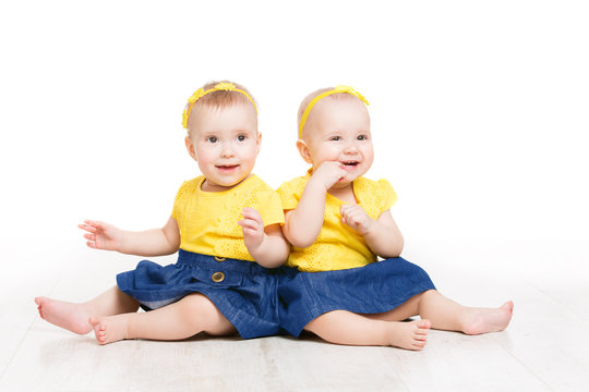 Babies Twins, Two Kids Girls Sitting on Floor, Happy Children Portrait, Sisters Isolated over White Background