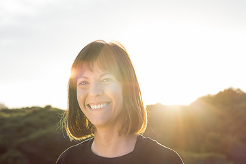 Normal brunette girl smiling. Woman with a smile on a sunset
