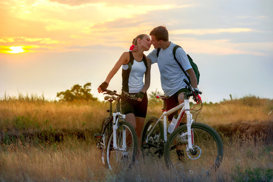 Beautiful young couple in love with bicycles at sunset