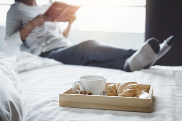 Relaxation and recreation, Young happiness woman on the bed with enjoying reading old book in holiday and morning cup of coffee and Croissant