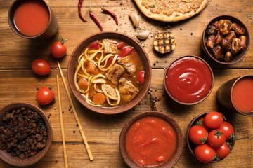 Asian beef soup. Traditional Uzbek dish is Lagman. Uzbek flatbread lavash, garlic, tomatoes, noodles, red pepper, eggplant, onion. Flat lay. Top view. Wooden background
