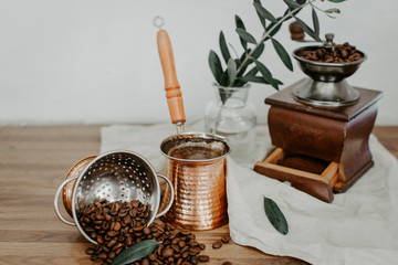 Turkish coffee in traditional embossed metal pot, coffee beens. Rustic background