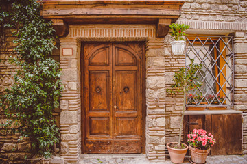 old building with wooden doors and potted plants on street in Castel Gandolfo, Rome suburb, Italy