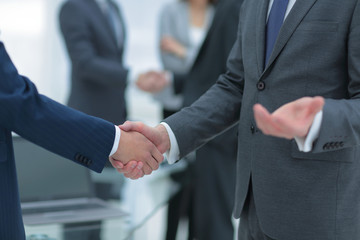 Business partners handshaking over business objects on workplace