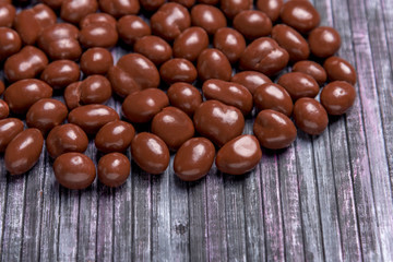 Peanuts in chocolate. Sweet peanut in the background. Wooden background. Sweet peanuts in chocolate for tea and coffee.
