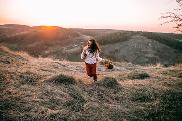 Portrait of a attractive young girl with a hat in the mountains at sunset. She resting and sitting wearing stylish fall outfit. Concept travel