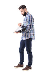 Side view of stylish bearded modern business man opening laptop computer. Full body isolated on...
