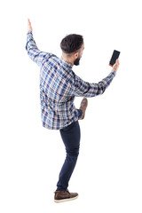 Excited young man holding mobile phone reading message on blank screen falling backwards. Rear view. Full body isolate on white background. 