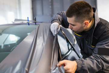 Car wrapping specialist putting vinyl foil or film on car. Selective focus. 