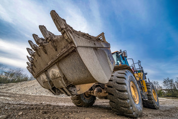 Yellow loader with a large bucket on the construction of the road.