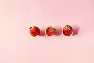 Fresh strawberries in waffle cups over pink pastel pin-up background. Copy space. Top view