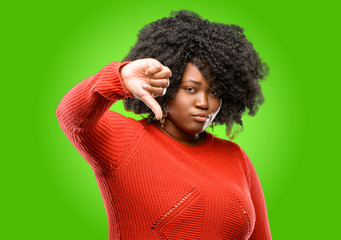 Beautiful african woman showing thumbs down unhappy sign of dislike, negative expression and...