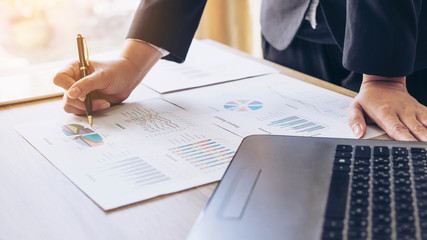 Image of  business people pointing at business document during discussion at meeting , Notebook on wood table