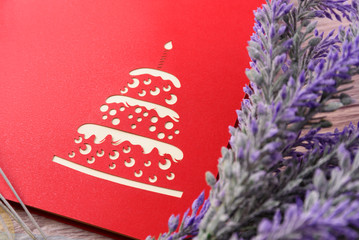 Red greeting card and lavender flowers on a light wooden background closeup