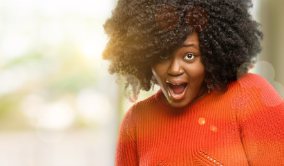 Beautiful african woman scared in shock, expressing panic and fear, outdoor