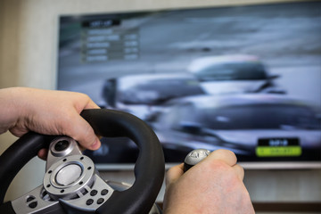 playing in the race behind the wheel of a game console in front of the big screen